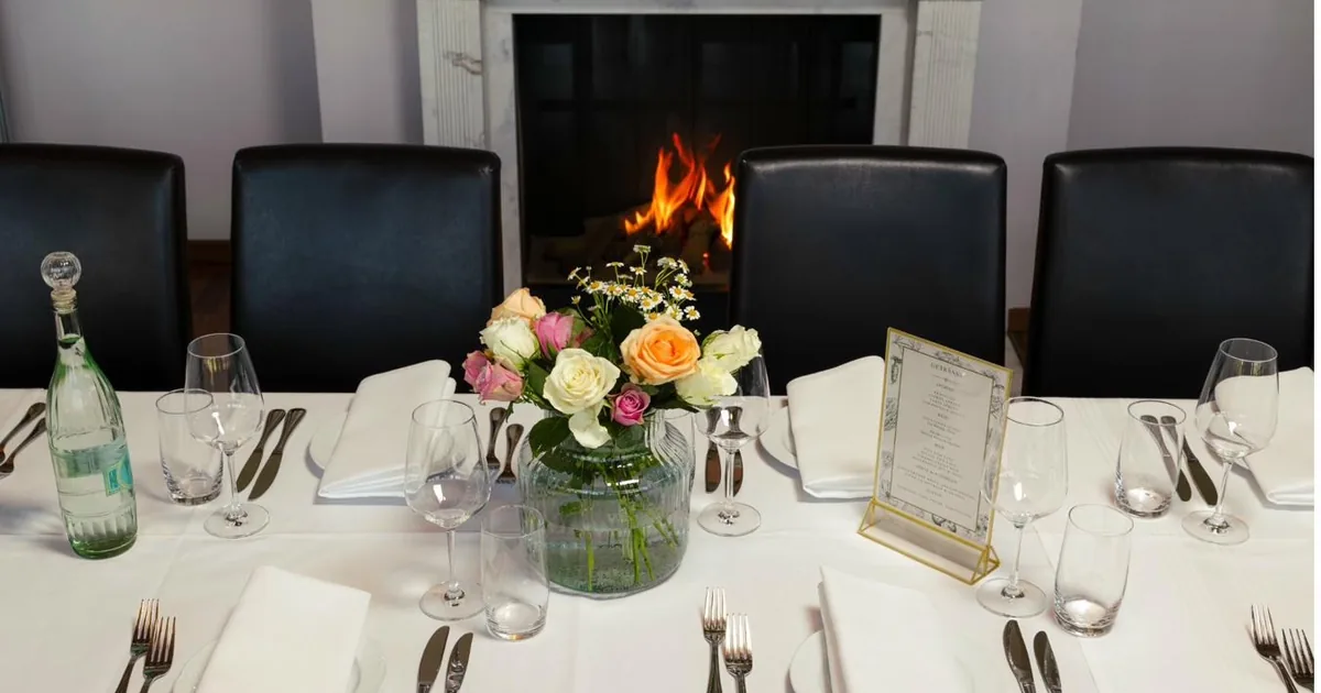 Festlich gedeckte Tafel mit Blumen und Menükarte vor dem Kamin im Kaminzimmer des Passions Restaurant Bad Homburg
